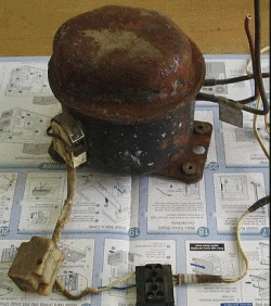 Rusty salvaged fridge compressor sitting on the build instructions